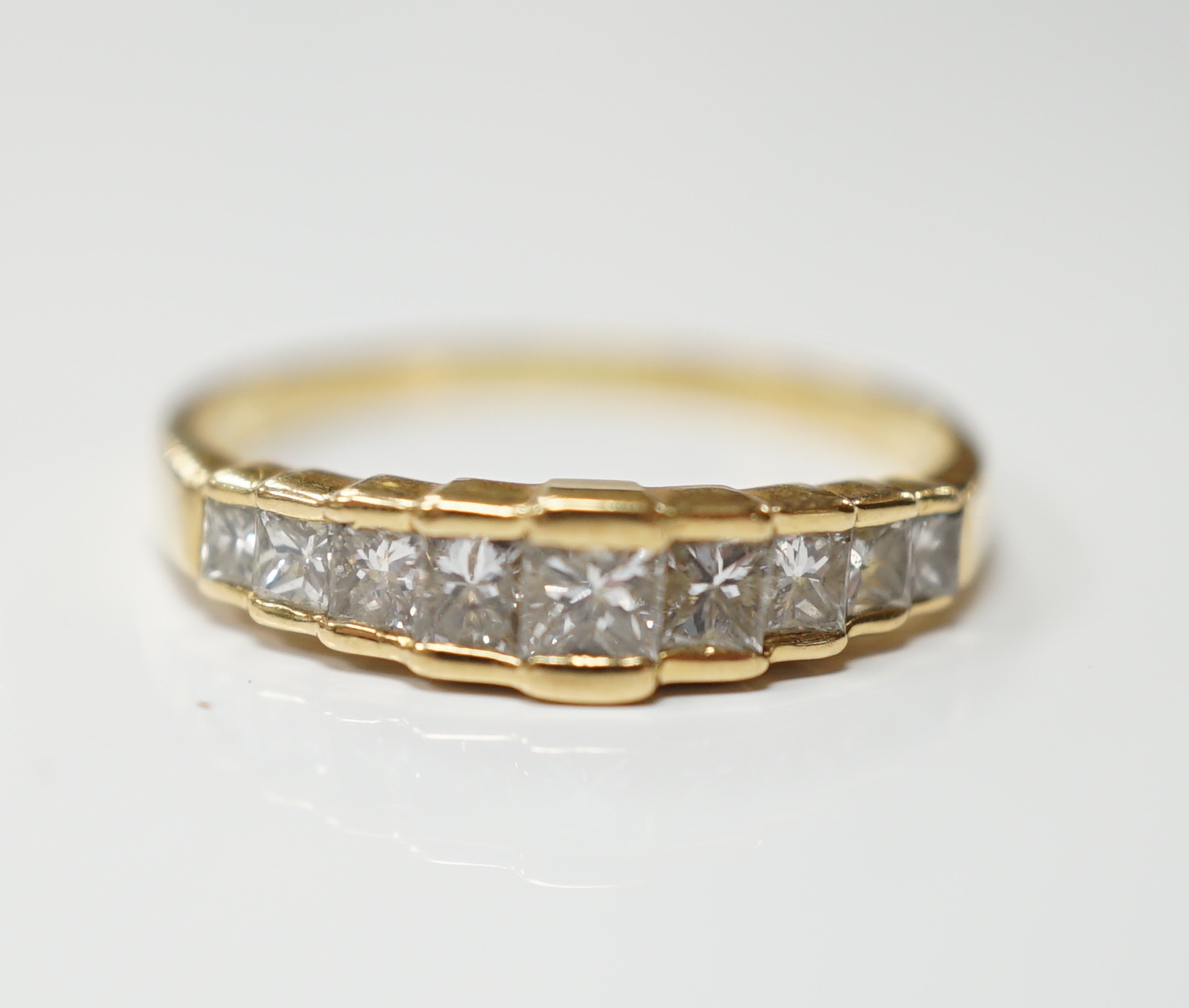 A modern 18ct gold and graduated nine stone princess cut diamond set half hoop ring, size L, gross weight 1.9 grams.